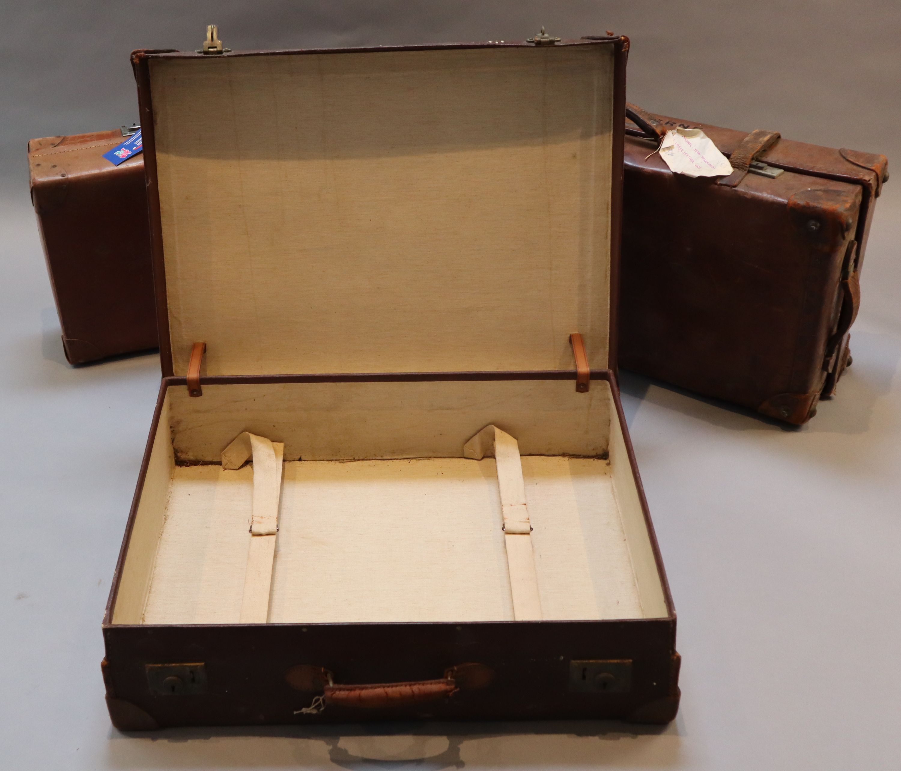 A group of three tan leather suitcases, one inscribed Brabourne, another Marchioness of Sligo